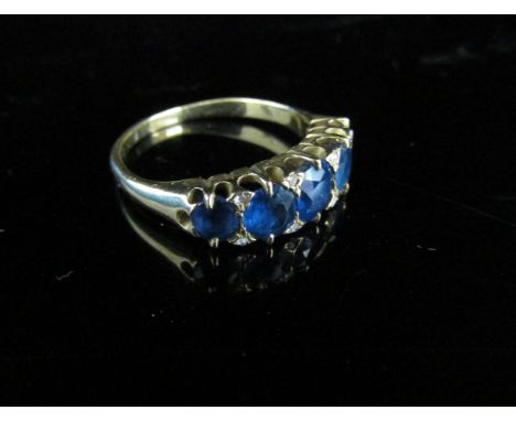 A sapphire and diamond ring the five oval graduated sapphires flanked top and bottom by small old cut diamonds. Size N/O, 3.8