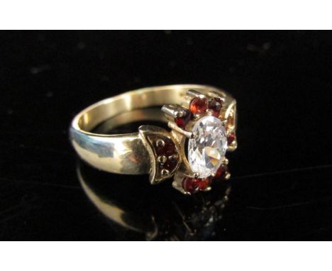 A 9ct gold ring centrally set with oval clear stone framed by garnets. Size S, 3.8g 