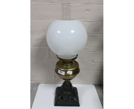 An antique brass oil lamp with glass chimney and shade on cast iron base 