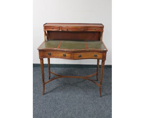 A mahogany serpentine fronted writing desk with three green leather inset panels with shelf above fitted three drawers 