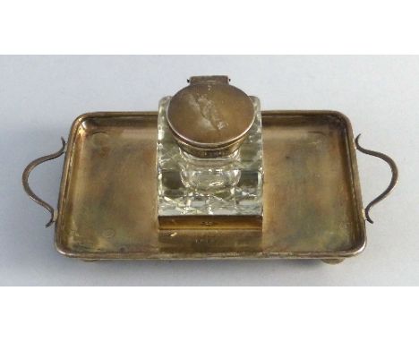 An ink stand, the base as a two handled rounded oblong tray on four bun feet with central framework containing a cuboid inkwe
