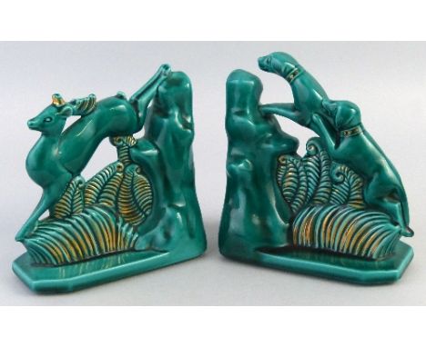 A pair of Art Deco style bookends, each green glazed with gilt highlights, one modelled as two hunting dogs the other as a de