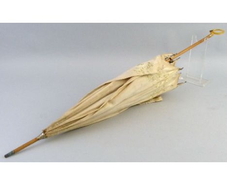 A late 19th/20th century parasol, the white covering printed with a floral pattern on cane stem with moulded ivorene ring han