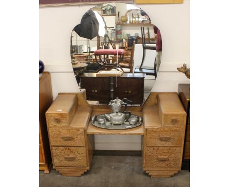 An Art Deco light oak dressing table, having shaped bevelled mirror above a stepped arrangement of drawers, 116cm