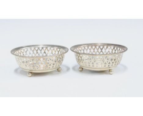 George V silver bonbon dishes, circular with pierced sides, raised on three bun feet, Birmingham 1911, 8cm diameter (2) 