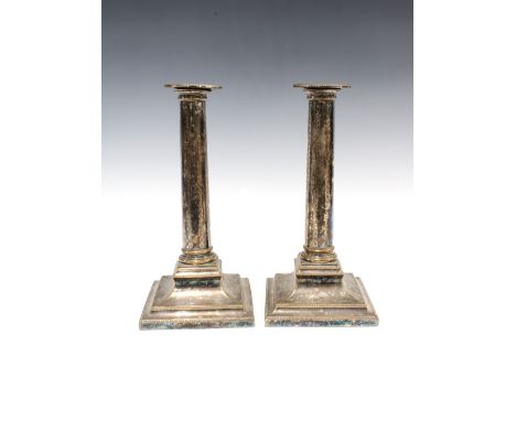 A pair of silver plate on copper candlesticks, engraved columns and standing on square stepped bases (2) 