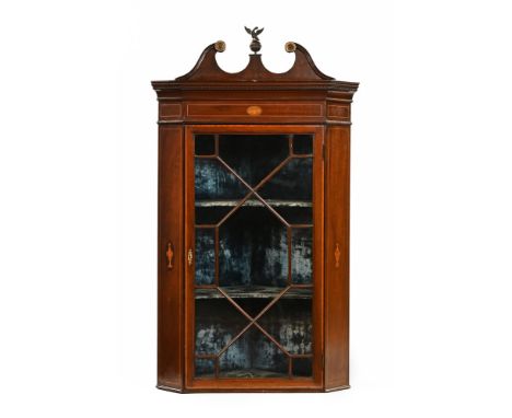 A 19th century inlaid mahogany hanging corner cupboard, with swans neck pediment and dentil cornice above a glazed door with 