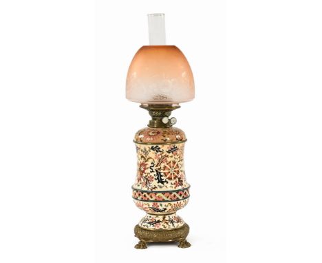 A Victorian ceramic oil lamp, double wick, the column with white ground and floral decoration above an embossed brass base wi