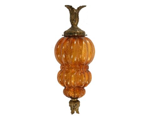 A moulded bulbous amber coloured glass lamp, with foliate gilt style fittings.  +/- 44 cm high.