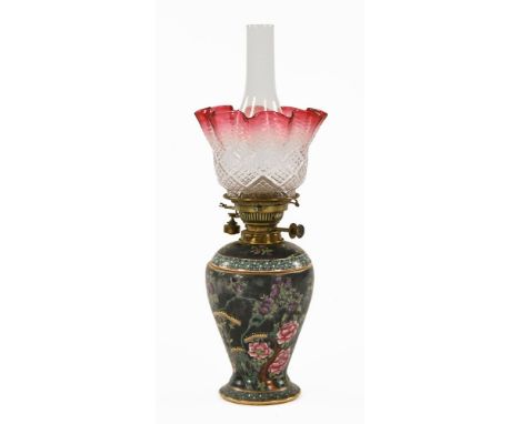 A Victorian porcelain and brass double wick oil lamp, with floral painted column on a circular base, with clear and cranberry