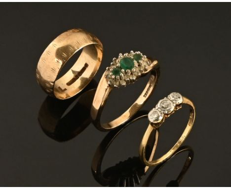 A 9 ct gold emerald and diamond cluster ring, a small 18 ct gold illusion set diamond ring and a 9 ct gold wedding band.  Wei