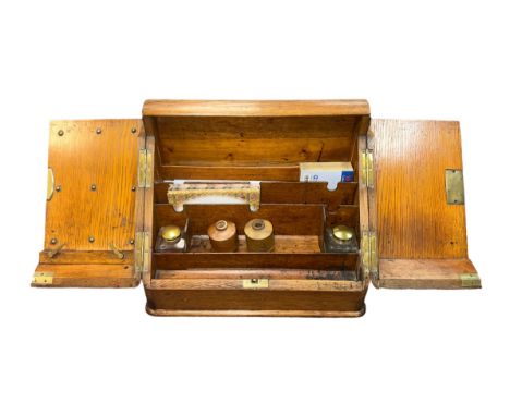 A two door hinged wooden writing slope with two inkwells and pen tray. Plus, two further ceramic ink wells. Height 30cm, widt