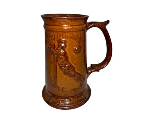 A Studio glazed Football tankard/stein/mug with image of a diving goalkeeper ‘the footballer’, lustre brown glaze, with handl