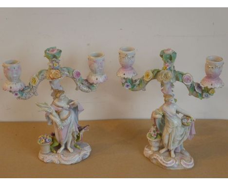 An interesting pair of 19th century hand-decorated continental porcelain two-light candelabra; each of figural form one unusu