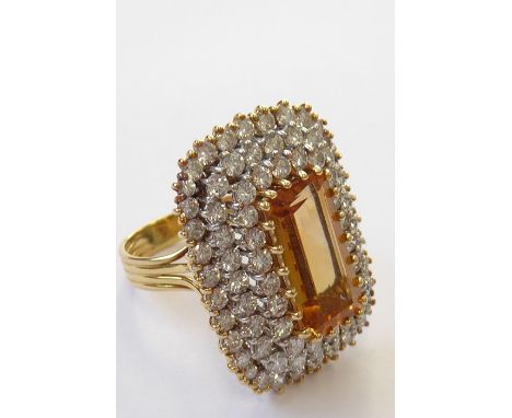 A topaz and diamond-set dress ring, the elongated rectangular-cut cornered topaz set above a three-tiered surround of brillia