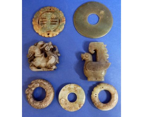 Seven Asian hardstone carvings comprising a bird finial, a Ming apple jade dragon disk, two dragon rings, an archaic Longshan