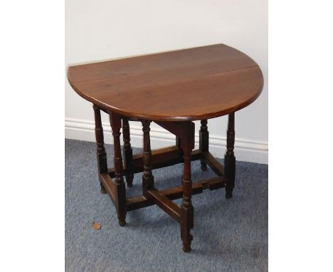 An antique oak drop-leaf gate leg table of small proportions; the oval top mounted on a (probably) 18th century base with tur