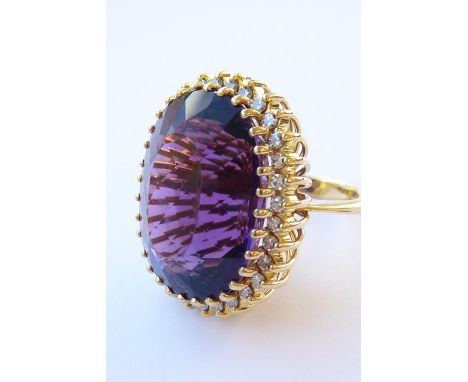 An amethyst and diamond-set dress ring, the oval mixed-cut amethyst claw-set above the brilliant-cut diamond set border, bask