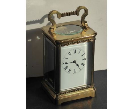 An early 20th century brass carriage clock timepiece; the swing handle above an enamel dial with Roman numerals (15cm high, w