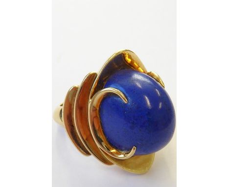 A stylish 1960s lapis lazuli dress ring, the oval lapis cabochon set above a concave navette plaque with pronounced crescent-