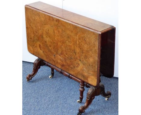 A 19th century figured walnut-topped drop-leaf gate-leg table; two turned swing-out legs on castors and the end supports carv