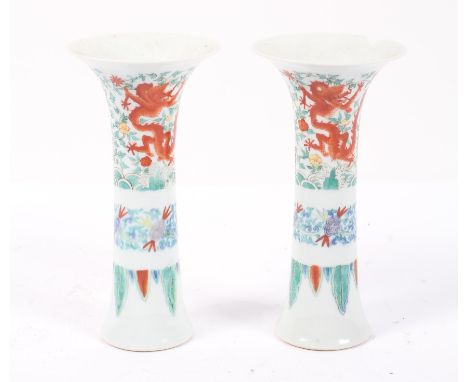 A pair of Chinese Doucai vases, Qianlong mark but probably later, of slender flaring form, with iron red dragons amongst foli
