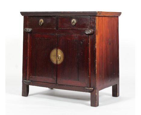 A Chinese hardwood cabinet, with two short drawers above two doors enclosing a shelf, with scroll/dog of fo carved ornament, 