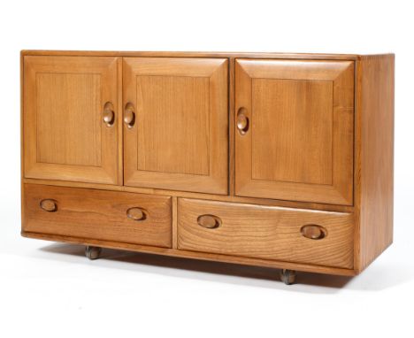 An Ercol blonde elm sideboard, with two door cupboard enclosing single shelf and a further cupboard with cutlery drawer, abov