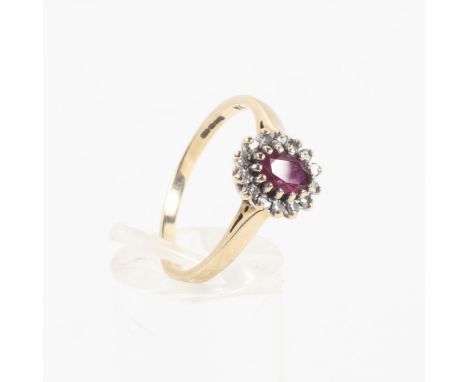 A yellow metal cluster ring principally set with an oval faceted ruby measuring approximately 5.50mm x 4.00mm and finished wi