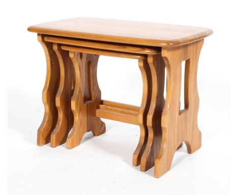 An Ercol blonde elm nest of three occasional tables, of rectangular form, on pierced serpentine supports, 42 cm high x 57 cm 