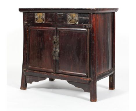 An Chinese ebonised hardwood cabinet, with two drawers above two panelled doors, with brass mounts, applied with scroll ornam