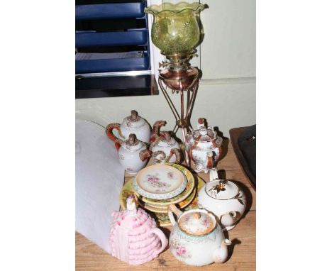 Oil lamp with glass shade, graduated serpent teapots, four decorative teapots and plaques.