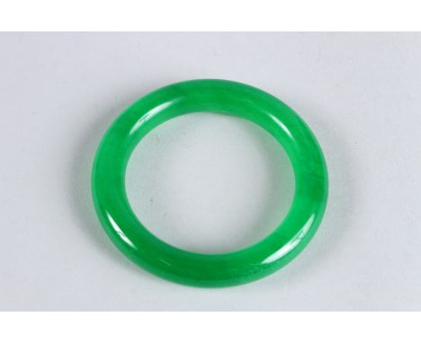 A CHINESE APPLE GREEN JADE BANGLE. 3.25ins diameter.