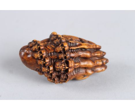 A HARDWOOD HAND AND SKULL NETSUKE. 2.5ins long.