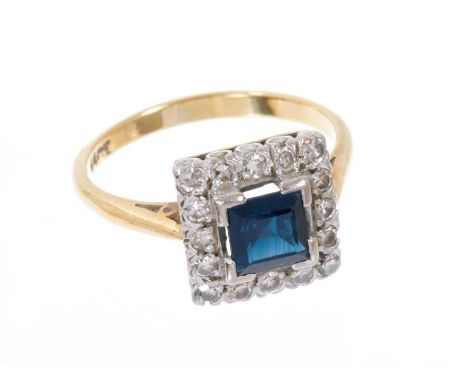 Sapphire and diamond cluster ring with a square step cut blue sapphire measuring approximately 5.4mm surrounded by a border o