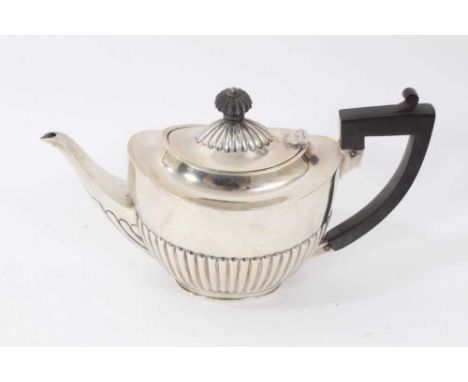 1920s silver teapot of oval form, with half fluted decoration, hinged oval cover and angular ebony handle, on an oval base (S