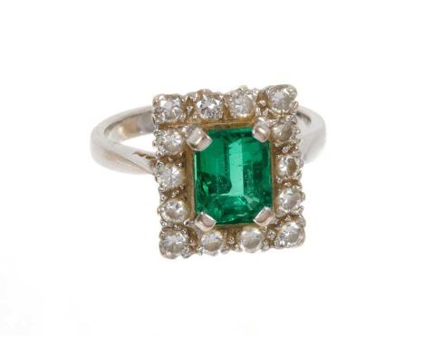 Emerald and diamond cluster ring with a rectangular step cut emerald measuring approximately 7.40mm x 5.89mm x 4.95surrounded