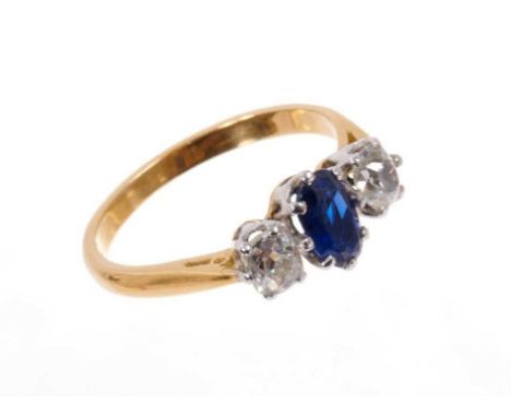 Sapphire and diamond three stone ring with an oval mixed cut blue sapphire flanked by two old cut cushion shape diamonds in c