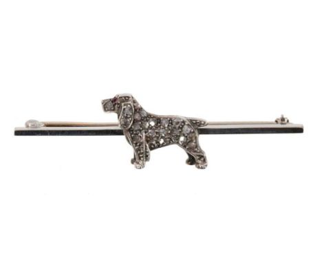 Novelty diamond set dog brooch, the stylised dog with ruby eye and pavé set rose cut diamond body on white gold bar brooch se