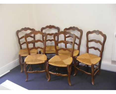 A set of six French fruitwood rush seated ladder back dining chairs. Raised on cabriole front supports united by turned stret
