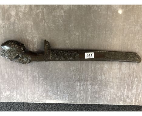 An Asian machete with carved pommel in the form of a head and a carved wooden scabbard.