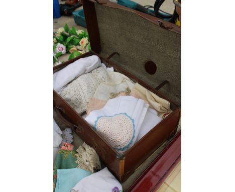 A VINTAGE TRAVEL CASE WITH A LARGE ASSORTMENT OF LINEN