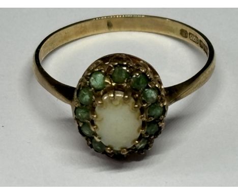A 9 CARAT GOLD RING WITH CENTRE OPAL SURROUNDED BY   EMERALDS SIZE R