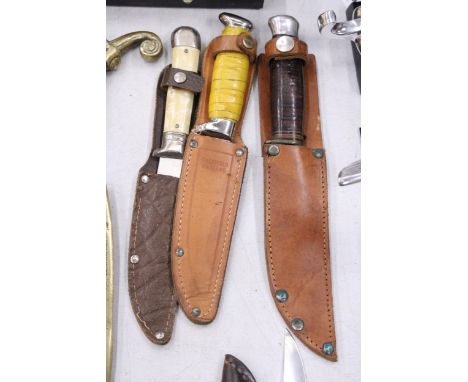 THREE VINTAGE DAGGERS IN LEATHER SHEATHS