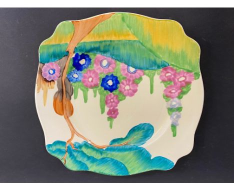 A Clarice Cliff Royal Staffordshire Pottery plate decorated with a garden scene of a tree and flowers, marked A.J. Wilkinson 