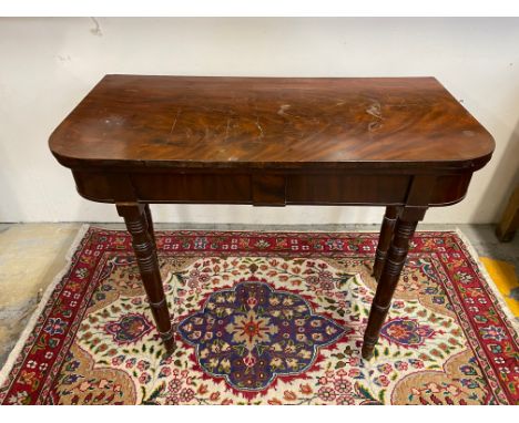 A 19th Century mahogany fold over card table with green baize interior raised upon ring turned supports, 36" wide.