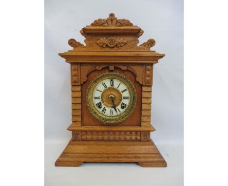 An Edwardian light oak mantle clock with a circular brass framed enamel dial, 12 1/2" wide x 17" high.