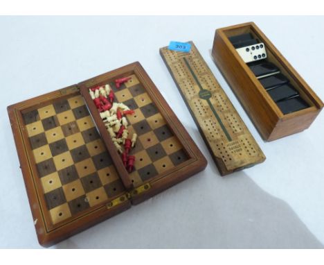 An early 20th century travelling chess set with red stained or natural ivory pieces, a set of dominoes and a cribbage board