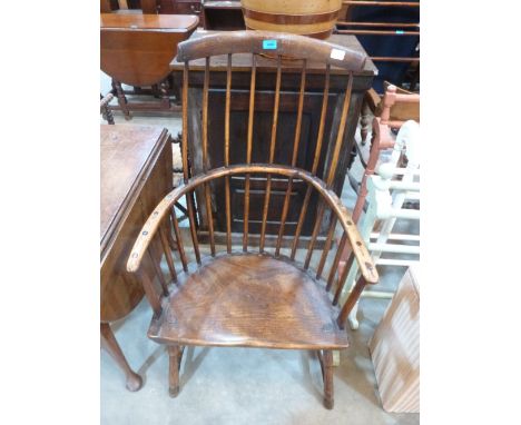 An early 19th century Welsh primitive Windsor elbow chair with comb back and bow arms, on turned splayed legs