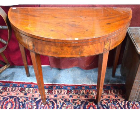A George III cross-banded mahogany demi-lune card table, the fold over top enclosing a baize lined surface, raised on square 